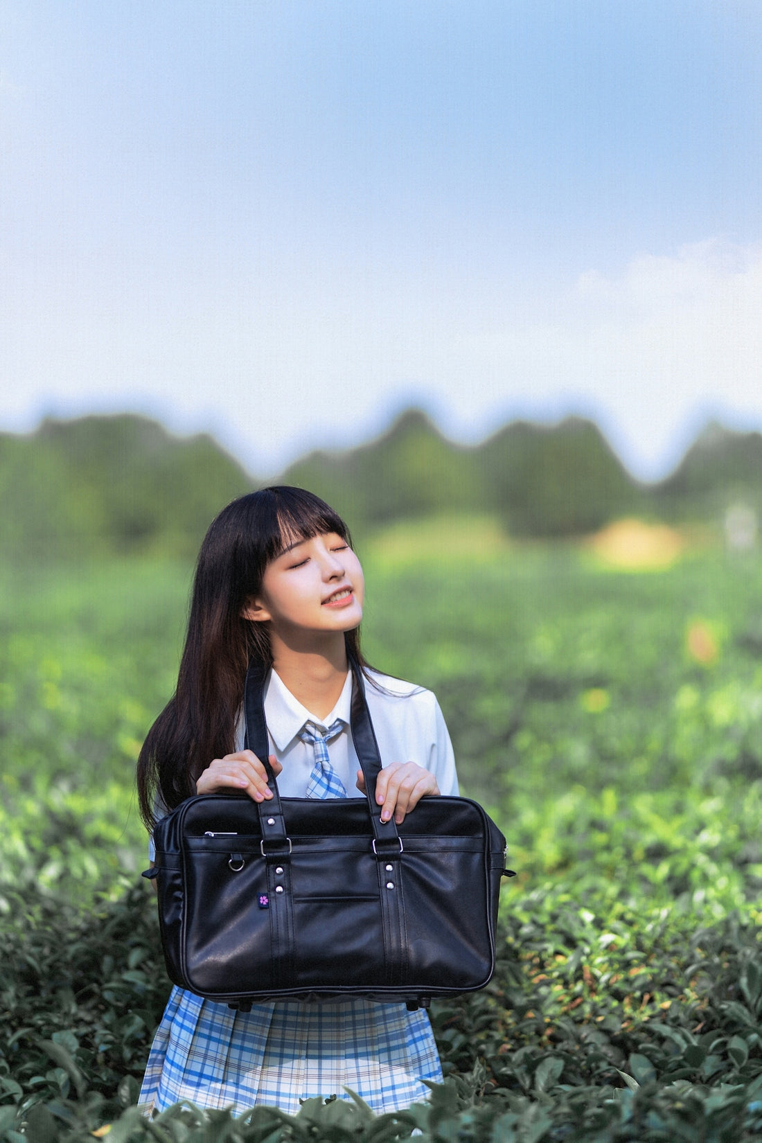 woman in white shirt and black leather sling bag standing on green grass field during daytime
